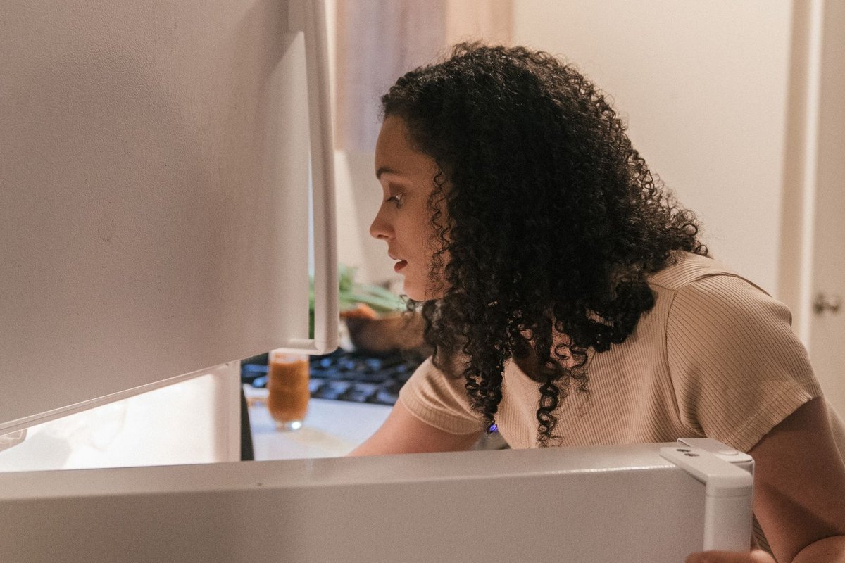 A person at an open refrigerator in a kitchen