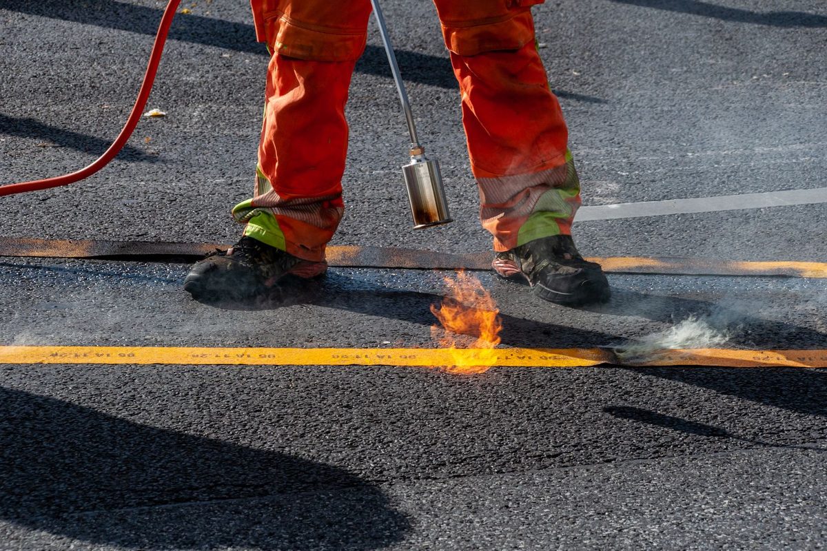 Sealcoat being applied to an asphalt surface in Anchorage