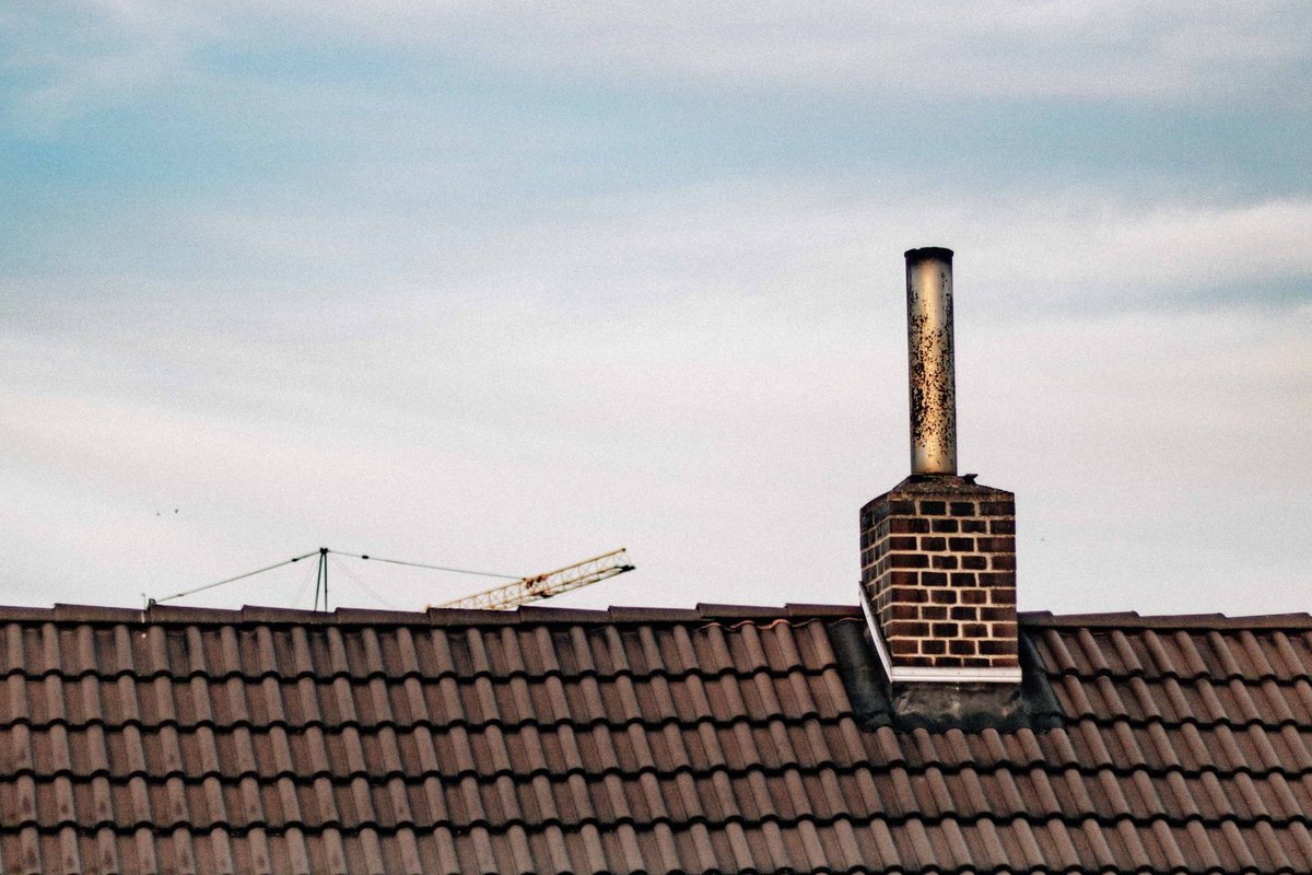 Brick chimney with a cap on a tiled roof in Anchorage, AK