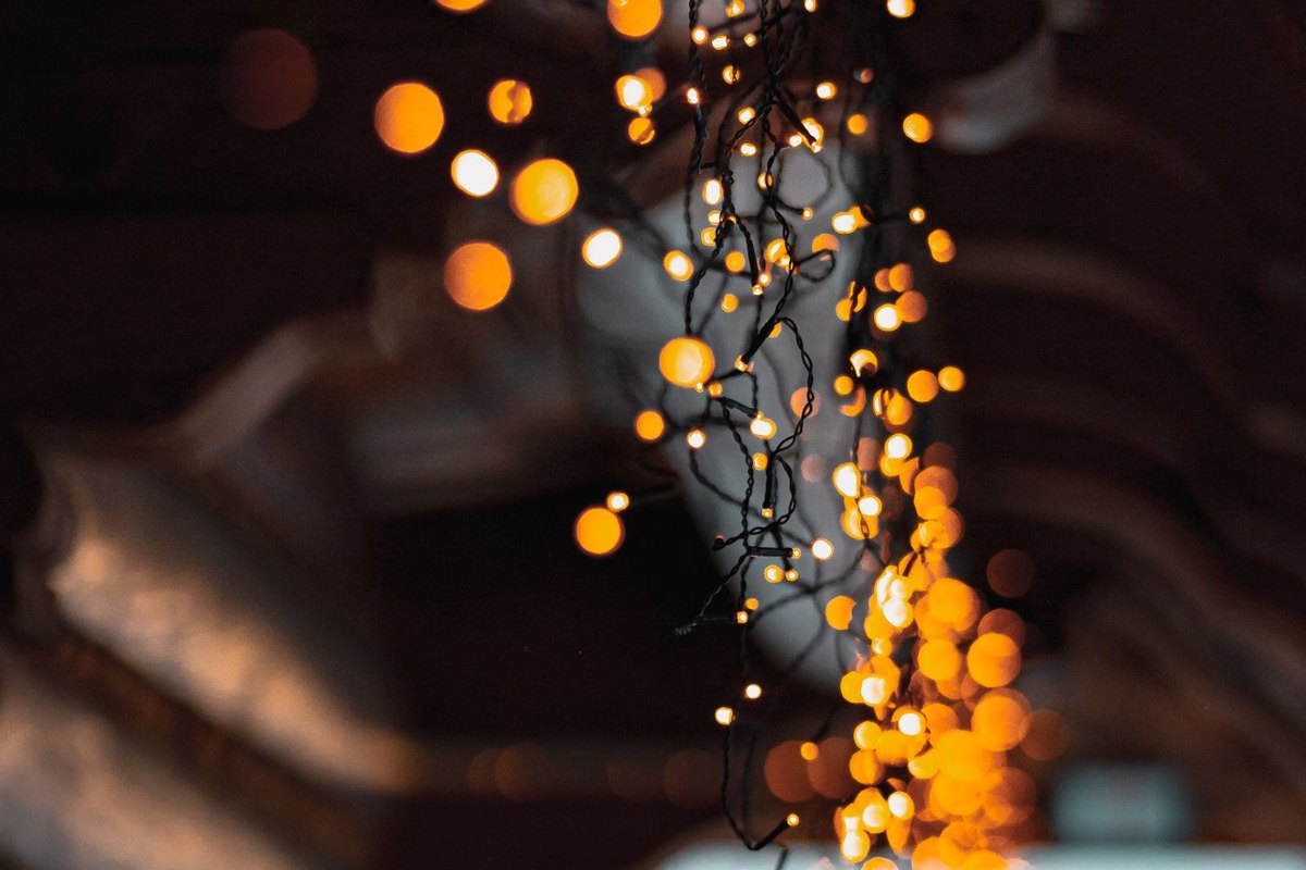 Warm string lights glowing along a roofline at night