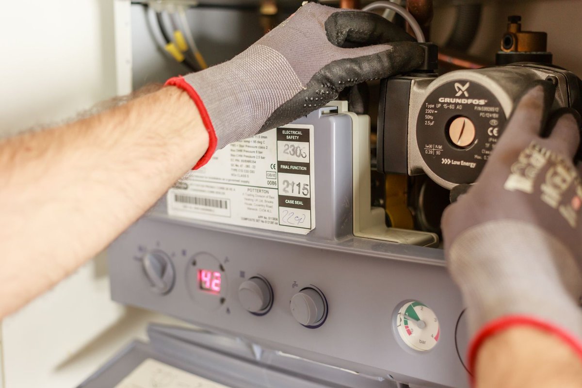Gloved hands working on plumbing equipment in Anchorage, AK
