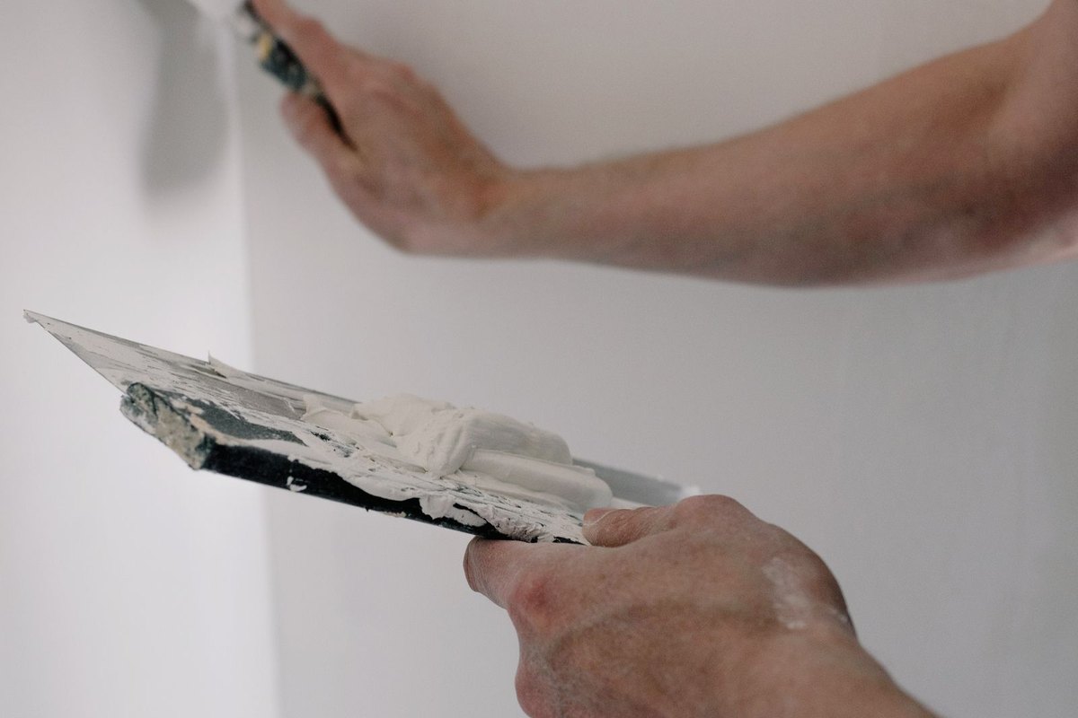 Applying joint compound over drywall tape with a taping knife