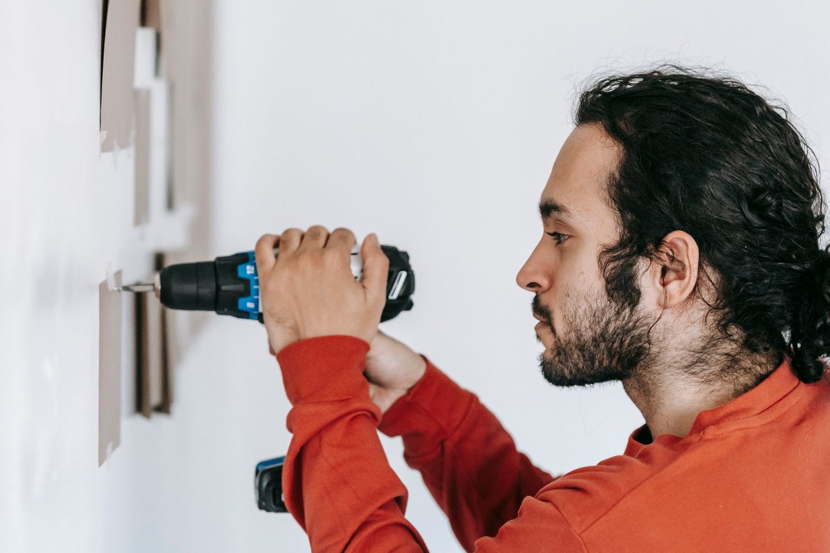 A person repairing something inside a Anchorage home with hand tools