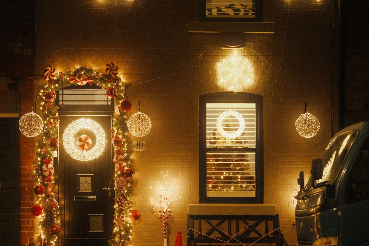Home entrance decorated with warm holiday lights and garland at night in Anchorage