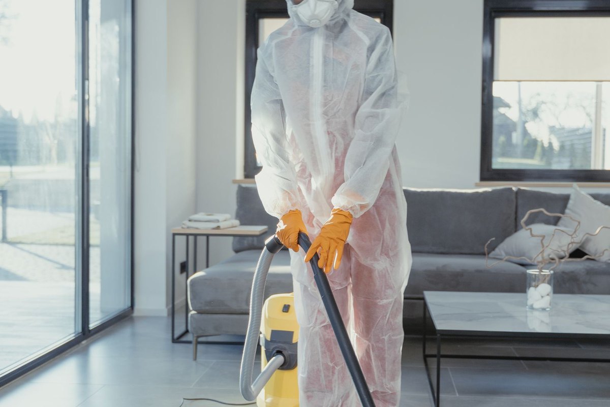 Worker in protective gear vacuuming a room during cleanup in Anchorage