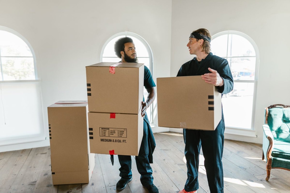 Two movers carrying boxes inside a home on moving day in Anchorage, AK