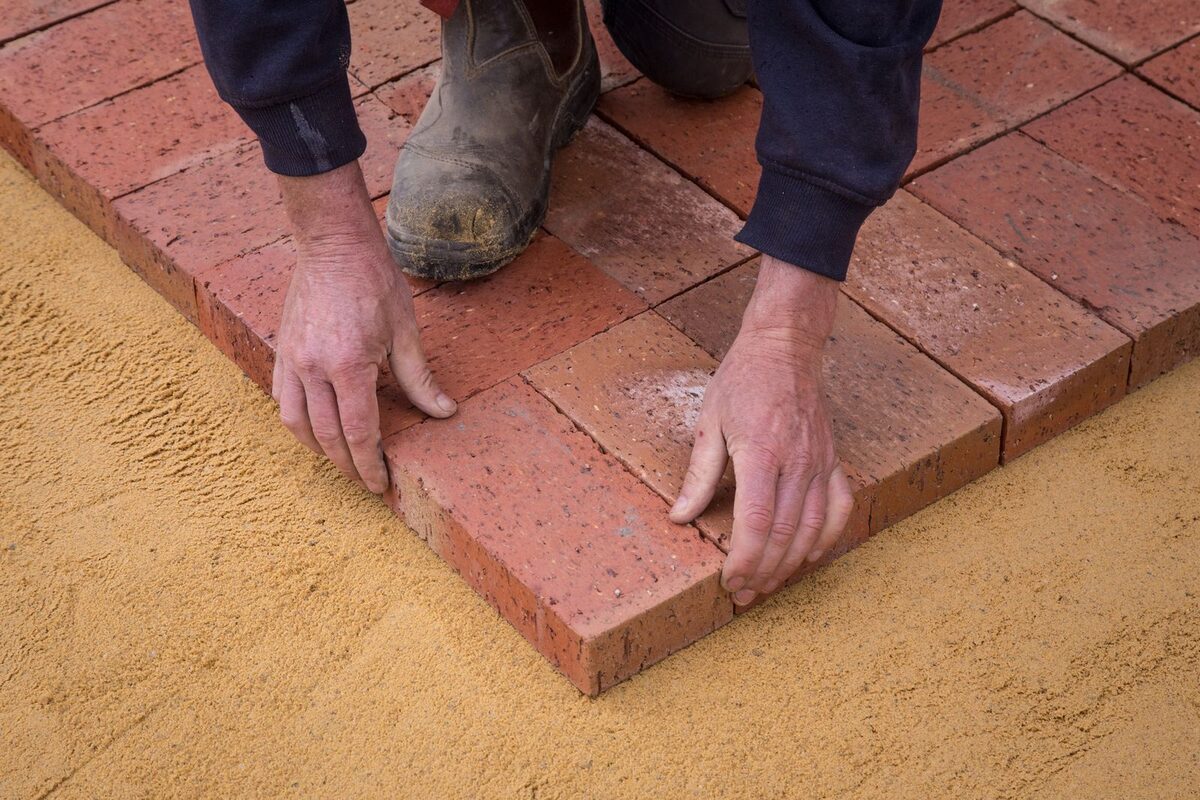 Setting a paver onto a prepared sand base over compacted gravel