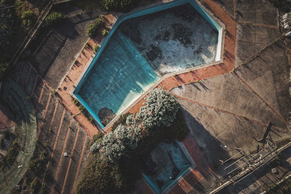 A neglected swimming pool with dirty, discolored water