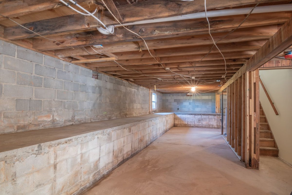 Unfinished basement with exposed floor joists and concrete block walls