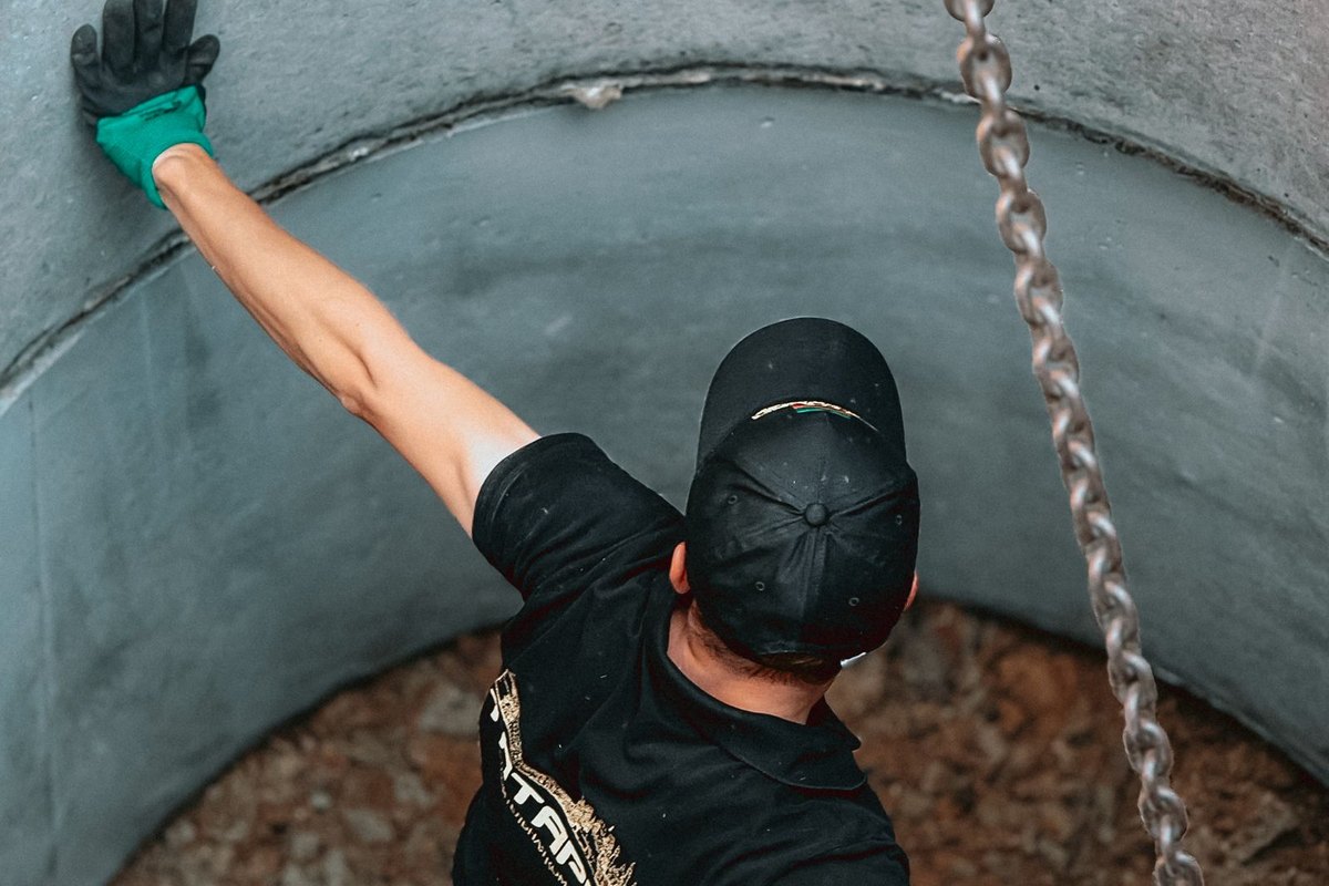 A worker reaching into a large concrete chamber