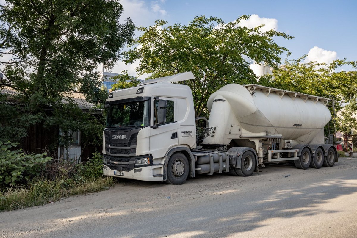 A tanker truck parked on a tree-lined street