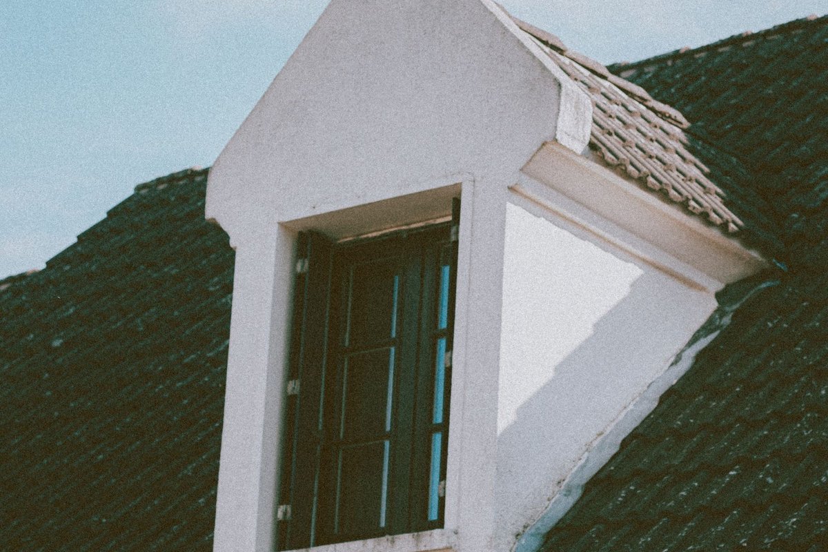 A window where a home wall meets a sloped roofline — the roof junctions where flashing keeps water out, in Anchorage, AK