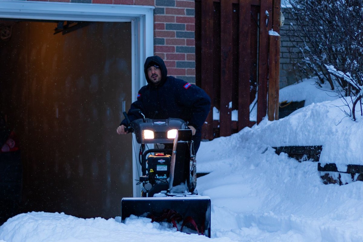 Clearing snow from a residential driveway with a snowblower in Anchorage, AK