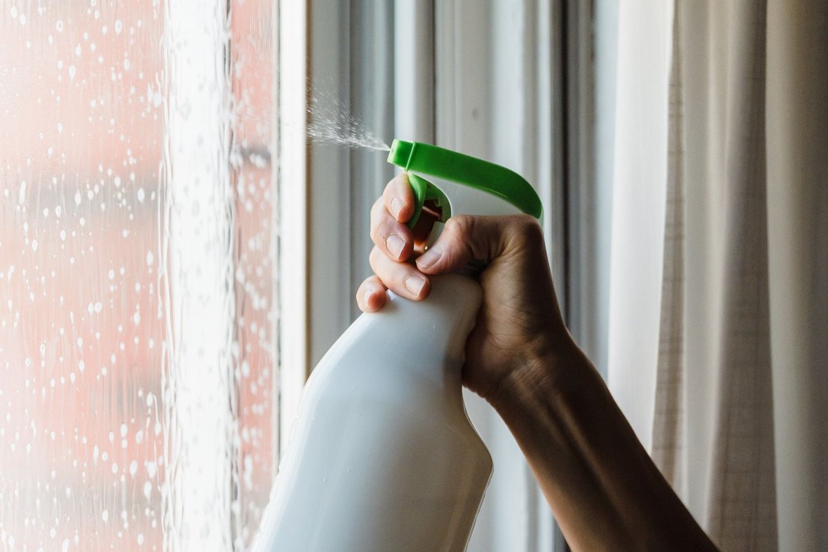 Spraying cleaning solution onto a spotted window pane in Anchorage, AK