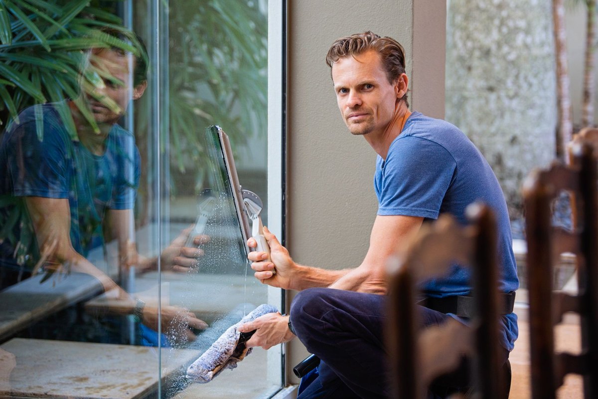 A person smoothing a large glass pane with a squeegee